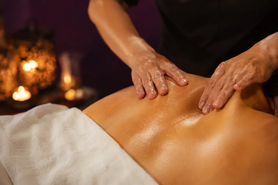 Lila Spa'da sırt masajı uygulaması — mum ışığında masaj odası